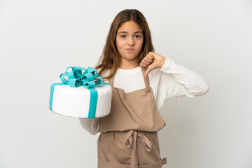 Little girl holding a big cake over isolated white background showing thumb down with negative...
