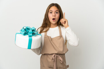 Little girl holding a big cake over isolated white background intending to realizes the solution while lifting a finger up