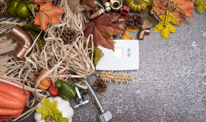 White thermostat and construction tools on autumn background with maple leaves and pumpkin. 
Thanksgiving  contractor holiday concept with copy space.  - obrazy, fototapety, plakaty