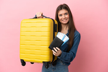 Young caucasian woman isolated on pink background in vacation with suitcase and passport