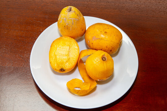 Cajarana, Canjarana, Caja-manga (Spondias cytherea), ripe in white plate on wooden table. Typical Brazilian fruit. Cajamanga