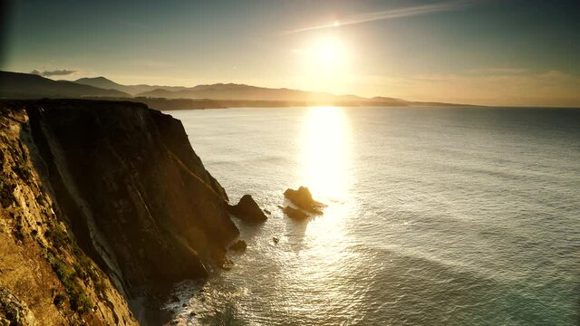 Sunset over rocky cliffs at Asturias coast in north Spain. View from Faro de Cabo Busto. Tourist attraction, place to visit.