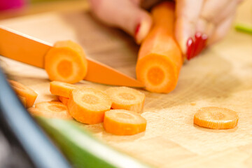 Woman cutting carrot on kitchen board