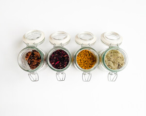 Jars of dried spices. Star anise, hibiscus flower, turmeric, lichen isolated on white background. Flat lay, top view.
