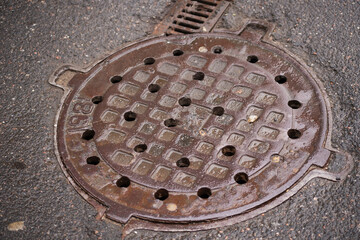 Metal covers of sewer manholes on city roads close-up.