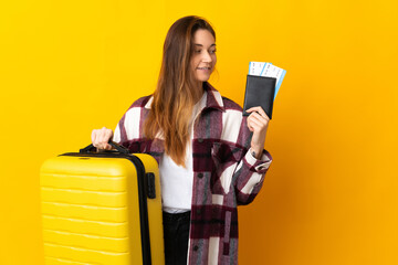 Young Ireland woman isolated on yellow background in vacation with suitcase and passport