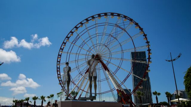 Batumi, Georgia - Moving sculptures of Ali and Nino in front of the Ferris wheel 4k uhd timelapse video