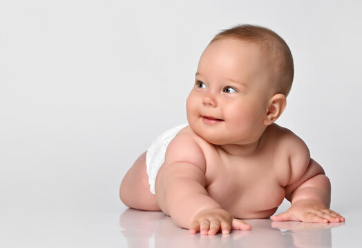 cute baby with a smile in a diaper looks towards the camera. Funny kid with smiling. Studio close-up portrait on white