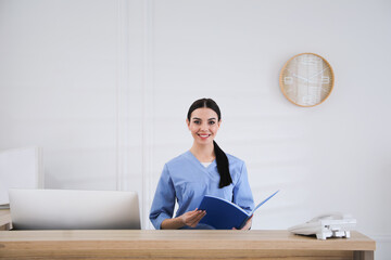 Receptionist with document case at countertop in hospital