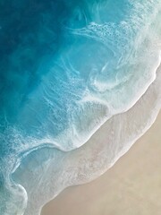 Aerial view of sea wave with white foam and light beige sand, diagonal. drawing epoxy resin. Close-up of deep rich blue, azure, turquoise color of water, shore. Summer sunny beach, seascape 