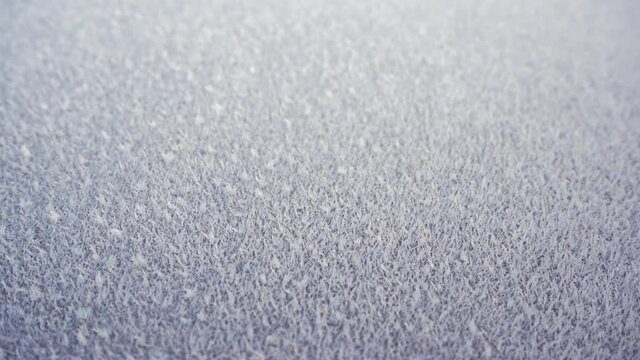 Glossy surface covered in frost frozen ice crystals, close up 4K slow motion