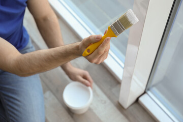 Man painting window frame at home, closeup