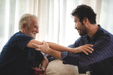 caucasian man surprise him adult father with giving gift box to celebration at home, family present to happy together lifestyle with love, people having fun and smiling in holiday