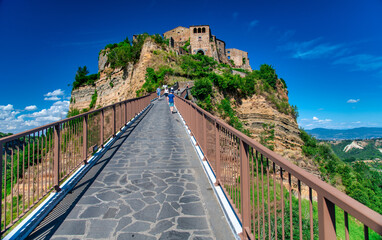 Fototapeta na wymiar CIVITA DI BAGNOREGIO, ITALY - JULY 2, 2021: Tourists walk along major bridge to reach medieval town.