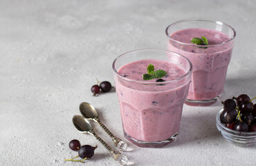 Natural yogurt with black currant in two glass on light gray background. Space for text