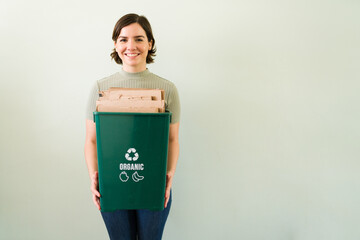 Portrait of a young woman recycling against a background