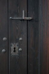Fragment starych, drewnianych drzwi z metalowym zamkiem i zamknięciem