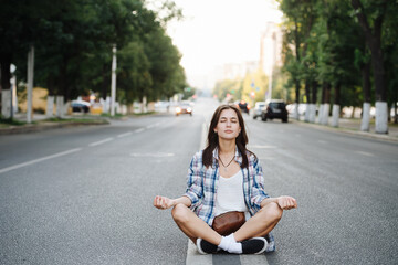 Peaceful woman meditating in easy pose in the middle of a city road