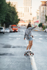 Adventurous woman riding on a skateboard on an empty city road early in morning