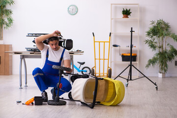 Young male repairer repairing perambulator indoors