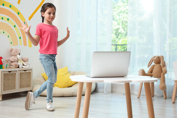 Cute little girl taking online dance class at home
