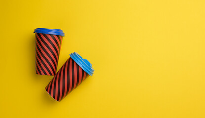 two paper red cups with a plastic lid on a yellow background, top view