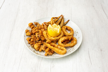 Andalusian fried shrimp, squid rings and breaded anchovies on a white plate