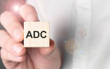 Man holding adc word on wooden cube.