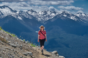 Fototapeta na wymiar Middle age woman walking in mountains in summer. Walking trail from Whistler gondola. Whislter Blackcomb Ski resort. British Columbia. Canada 