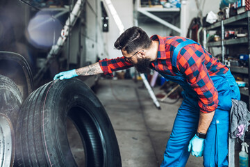 Mechanic pulls tire from the warehouse. Vehicle repair service.