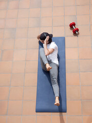 Young man doing sit-ups on mat on terrace outdoor