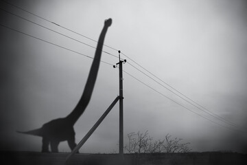 Silhouette of huge brontosaurus in dark fog and pillar with electric wires, gloomy fantastic collage