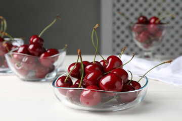 Sweet red cherries in bowl on white wooden table