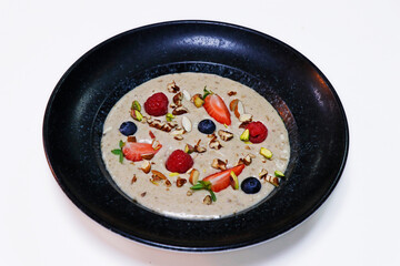 oat porridge meal with fresh mixed berries and dry nuts in a bowl