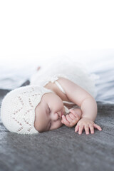 The baby is sleeping under a white blanket on the bed.