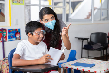 Mexican young teacher with student at school wearing face mask after coronavirus pandemic 