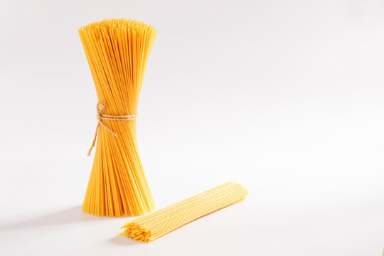 Top view of a bunch of bucatini or perciatelli - pasta, spaghetti on a white background. There was a faint sunlight coming from behind.