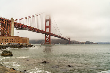 The famous Golden Gate Bridge in the fog. View from the south coast, from the Fort Point embankment.