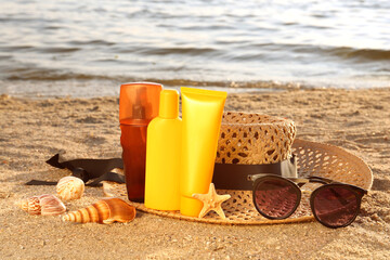 Sun protection products and beach accessories on sand near sea
