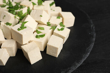 Delicious tofu with parsley on black table, closeup