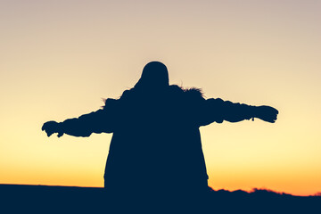 silhouette of woman standing and looking sunset.