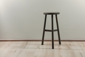 Stylish wooden stool near light wall indoors. Space for text