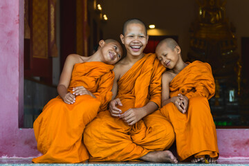 Obraz na płótnie Canvas buddhist novice monks smiling and sitting together at temple gate