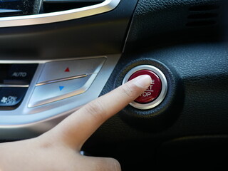 finger driver pressing on button to start stop engine of car.
