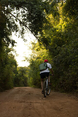 Hombre montando una bicicleta de montaña en un sendero verde, haciendo deporte en la selva