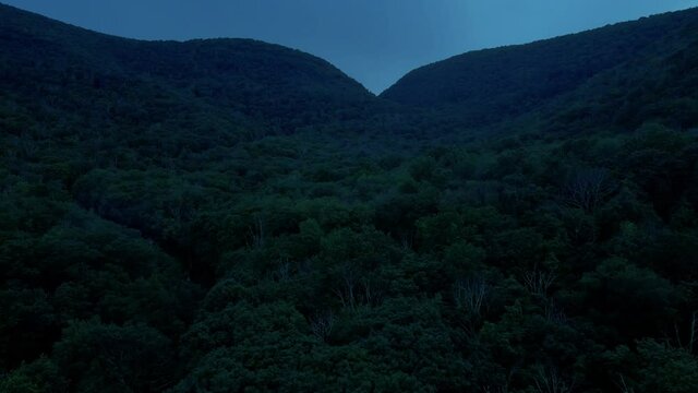 Aerial drone video footage of the Appalachian mountains after sunset during warm summer nights. This is in New York's Hudson Valley in the Catskill Mountain sub-range.	