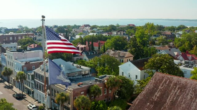 USA flag in Charleston, aerial pullback reveals St. Michael's church in historic city in South Carolina, SC, USA.