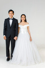 Fototapeta na wymiar Full Length of young attractive Asian couple, soon to be bride and groom, woman wearing white wedding gown. Man wearing black tuxedo, standing together. Concept for pre wedding photography