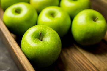 Freshly harvested green apples in the wooden crate. Selective focus.