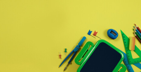 Stationery is on a yellow background. Top view of a lunch box, compasses and colored pencils on a yellow background. Education concept.